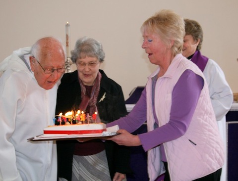 Harold Barber blows out the candles on his birthday cake. Next to Harold is wife Rae, Penny Ellis os presenting the cake, while the Rev'd Stefanie Hodges, looks on.